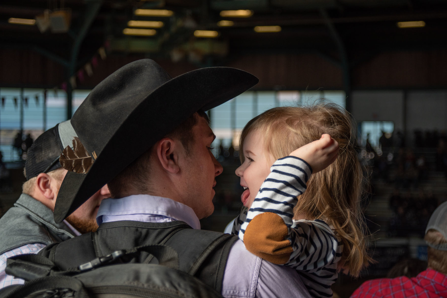 Nathan Rempe looks at his daughter Josie Rempe, 3, at the 64th annual K-State Rodeo on Saturday.